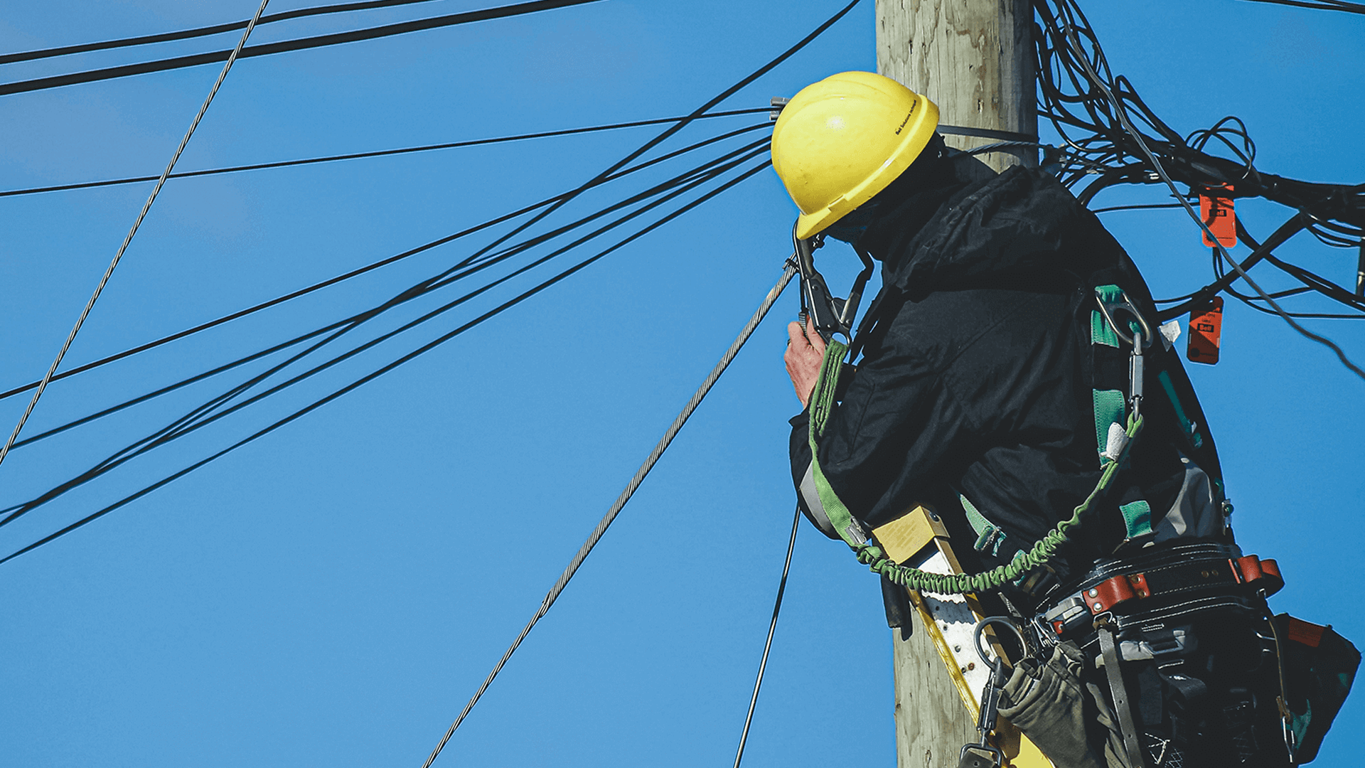 lineman wearing yellow hat working on power lines